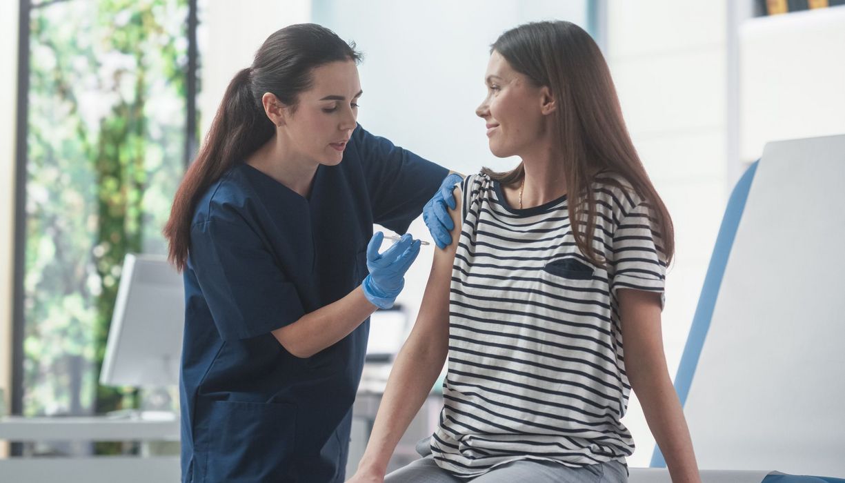 Krankenschwester impft eine junge Frau.