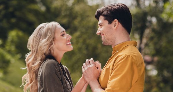 Ein Paar hält sich an den Händen und strahlt sich an.