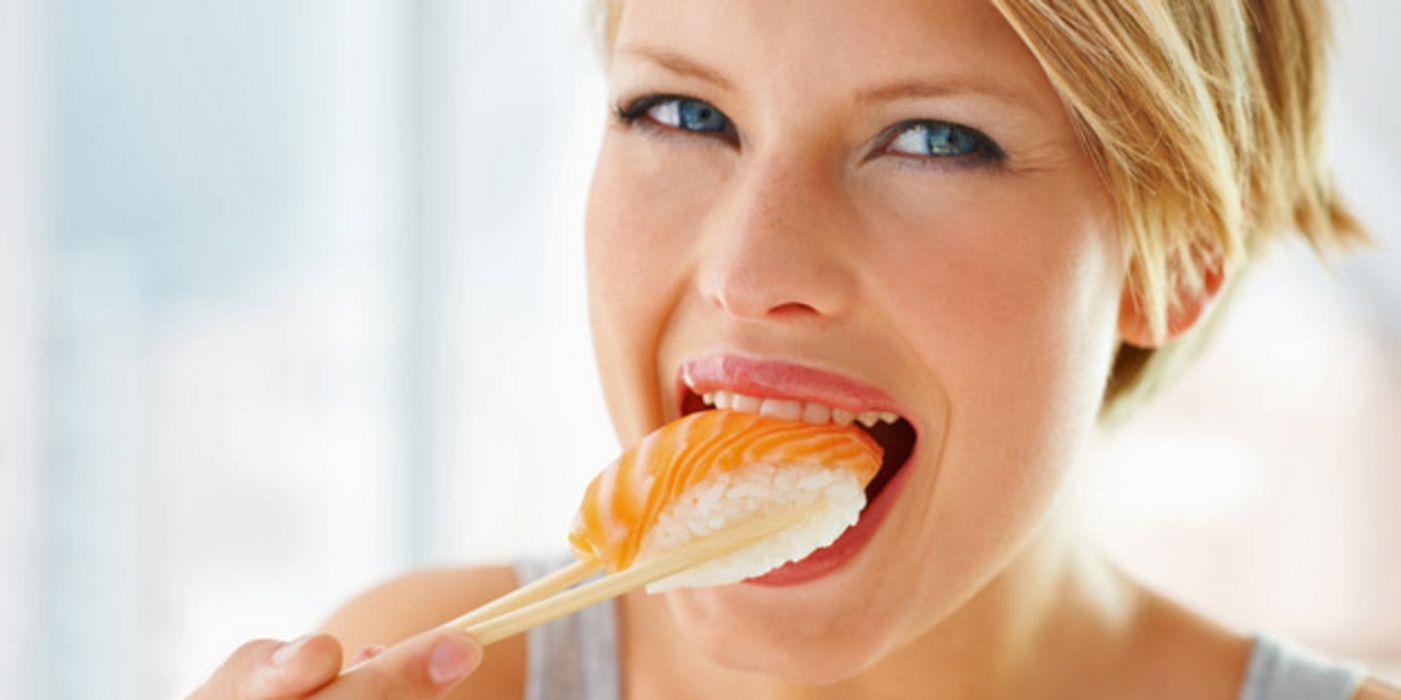 Frau isst Sushi mit Fisch