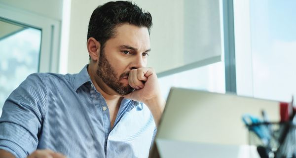 Mann, sitzt vor dem Laptop, Faust geballt.