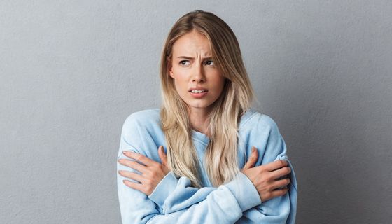 Junge Frau in hellblauem Pulli friert.