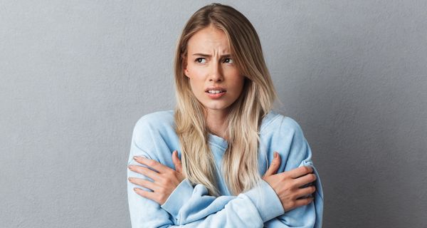 Junge Frau in hellblauem Pulli friert.