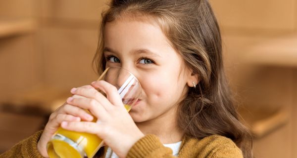 Kind, trinkt ein Glas Orangensaft. 