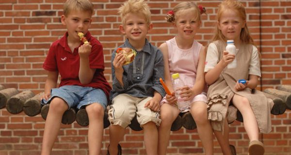 Vier Grundschüler nebeneinander essen ihr Pausenbrot
