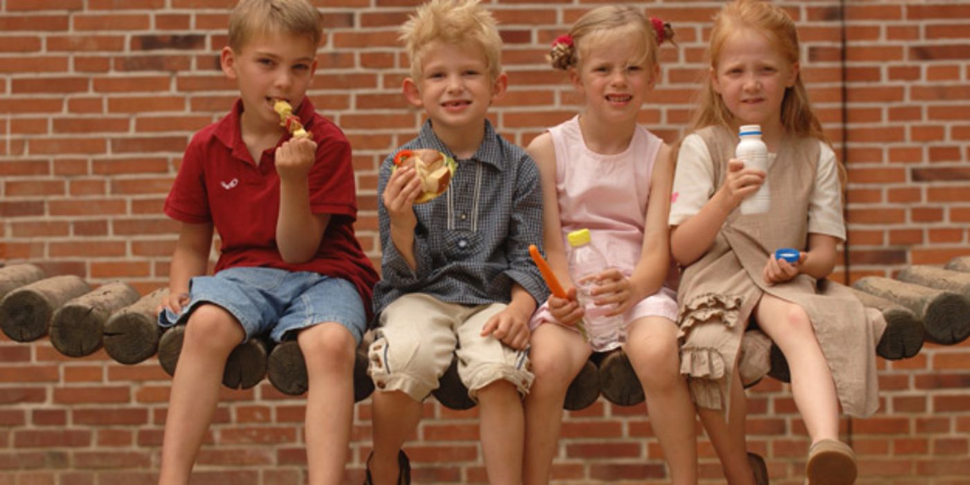 Vier Grundschüler nebeneinander essen ihr Pausenbrot