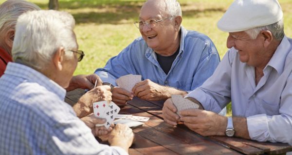 Vier vergnüge Senioren im Park an einem Tisch beim Kartenspielen