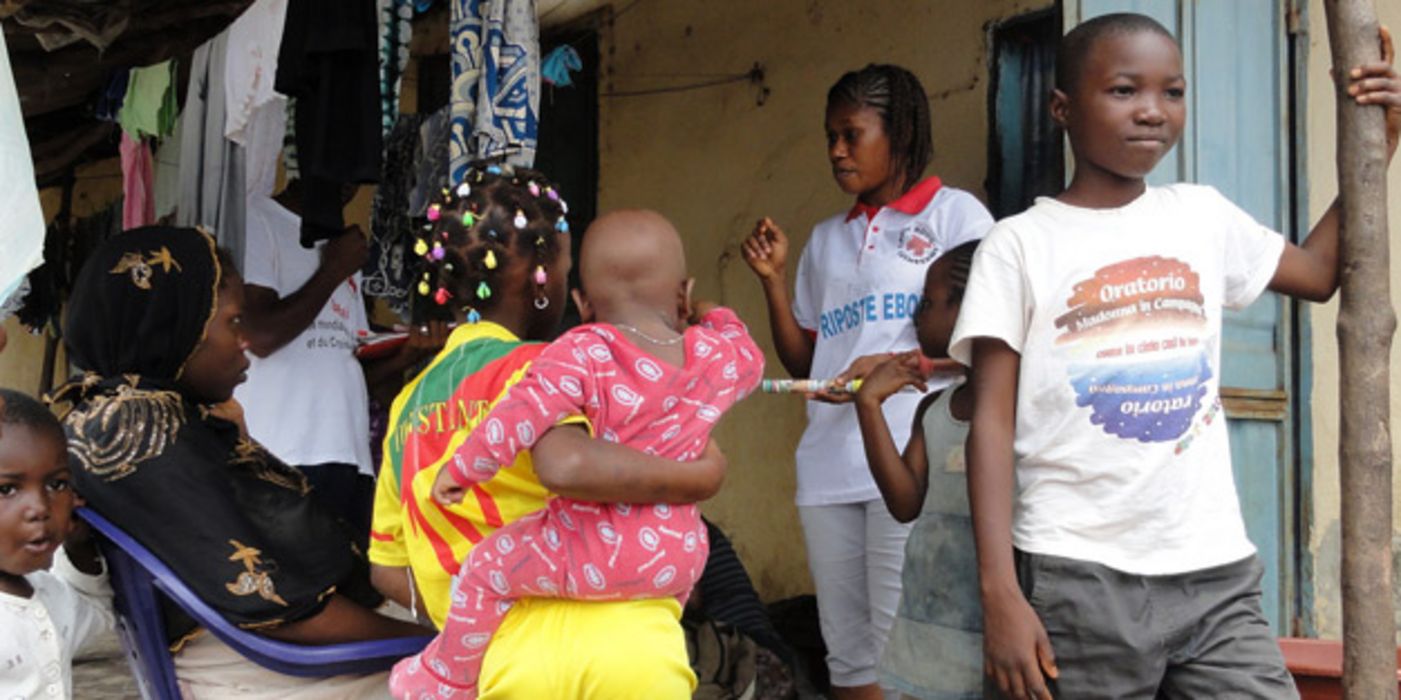 Mitarbeiterin des Roten Kreuzes in Guinea spricht mit Frauen und Kindern.