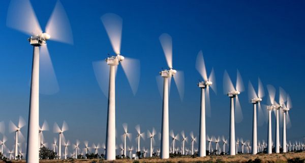 Rotierende Windräder in eine Reihe vor blauem Himmel