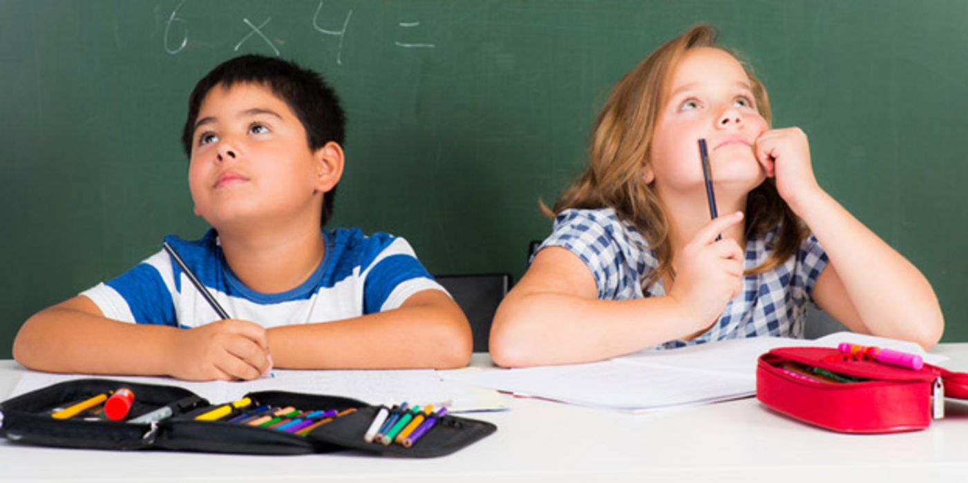Übergewichtige Schülerin und Schüler, ca. 11 Jahre alt, im Klassenraum vor einer Wandtafel mit Matheaufgaben sitzend. Beide schauen nach oben