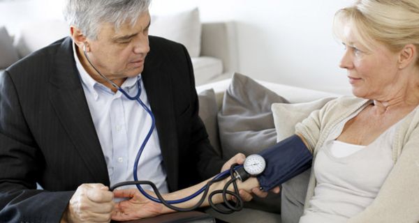 Arzt um die 50 misst bei einer Frau um die 50 den Blutdruck