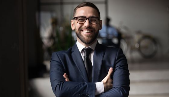 Jüngerer Mann mit Anzug, schaut in die Kamera.
