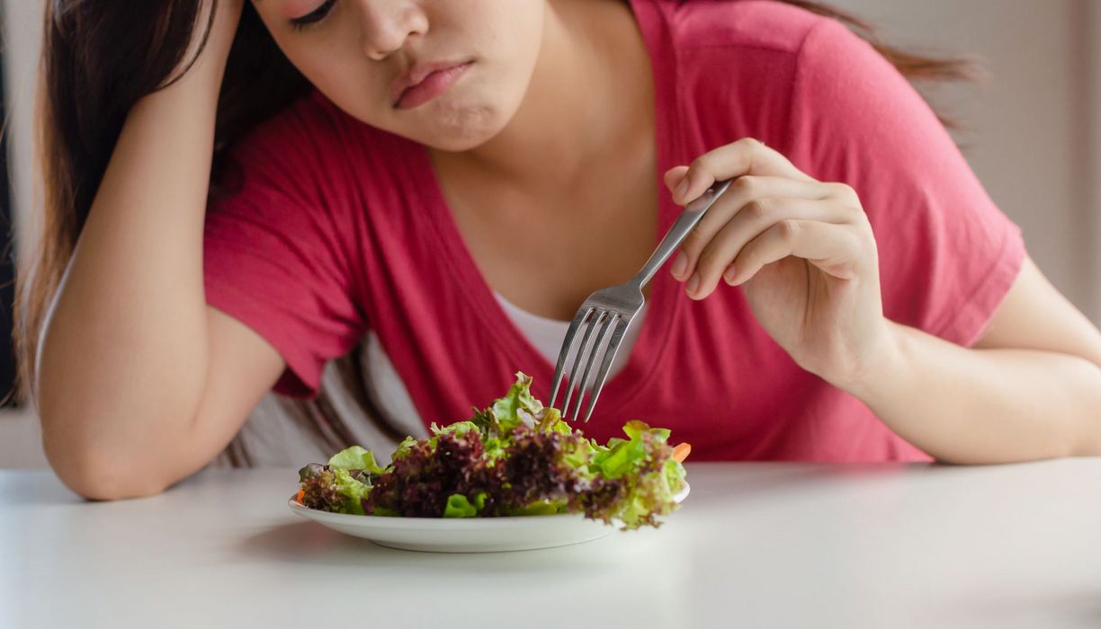 Frau, stochert in einem Salat herum.