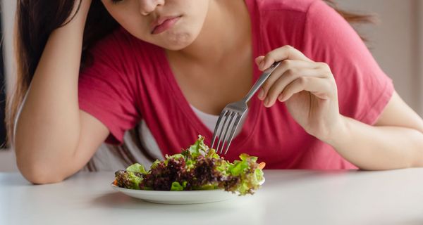 Frau, stochert in einem Salat herum.