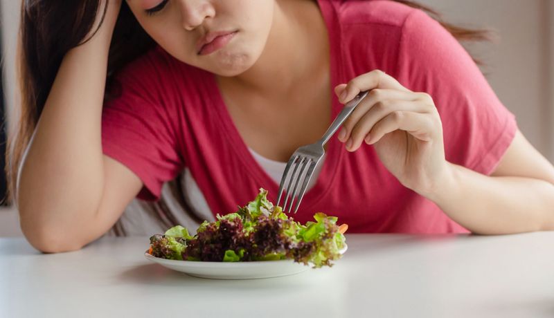 Frau, stochert in einem Salat herum.
