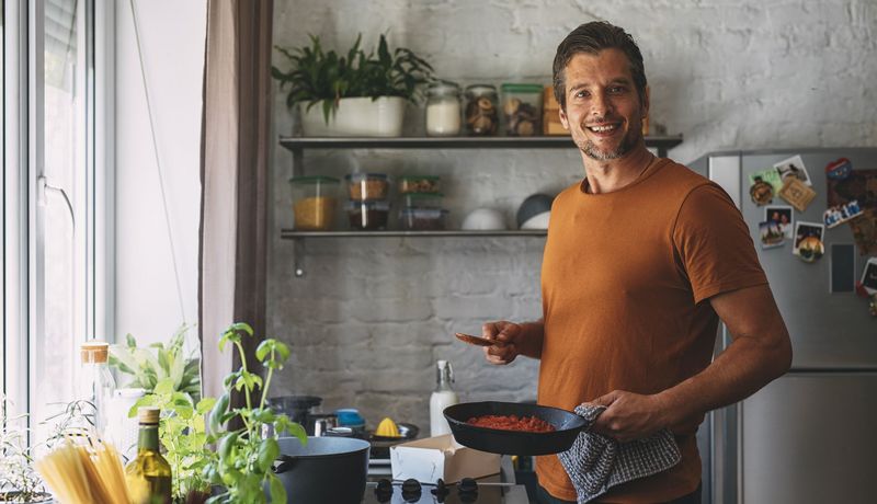 Junger Mann kocht in der Küche.