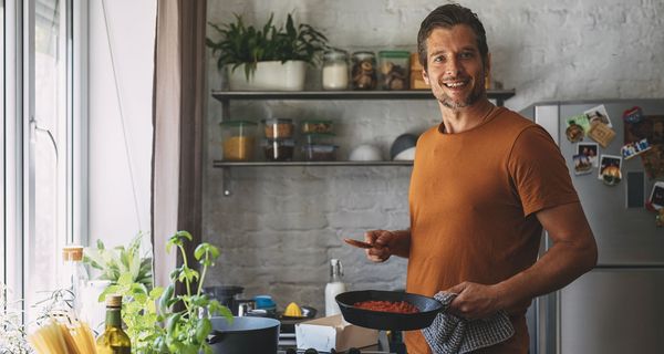 Junger Mann kocht in der Küche.