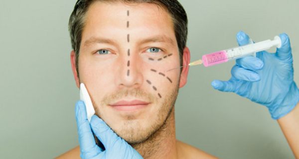 Mann mit Operations-Markierungen im Gesicht bekommt eine Spritze in die Wange injiziert