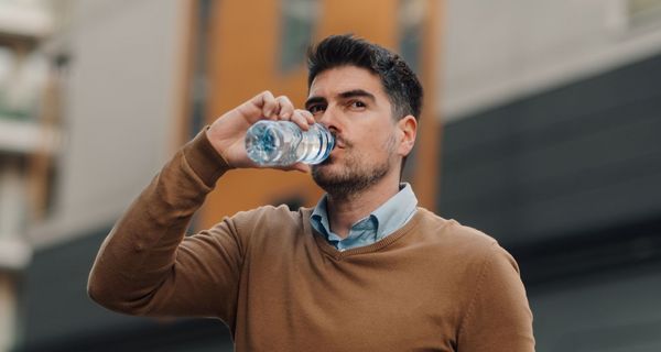 Junger Mann trinkt Wasser aus einer Plastikflasche.