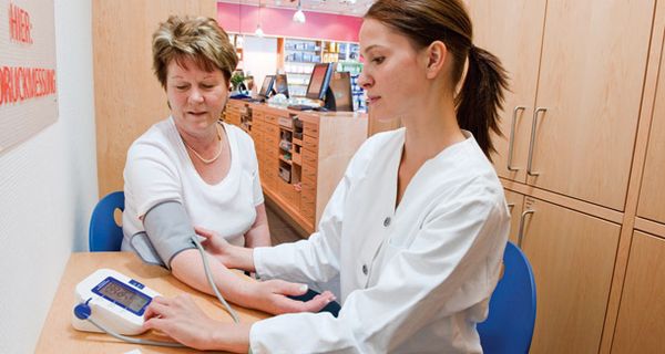 Seniorin bei der Blutdruckmessung in einer Apotheke