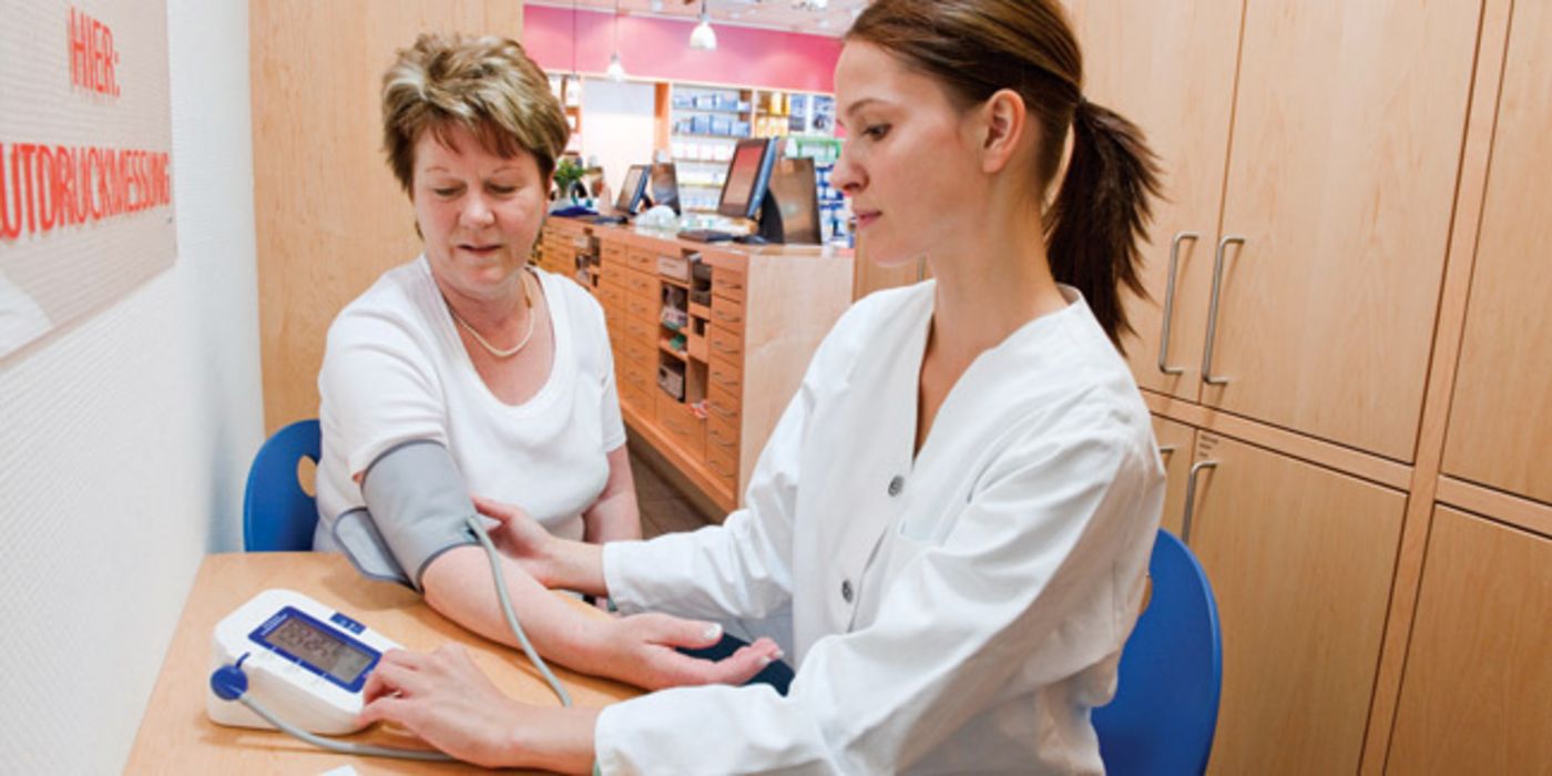 Seniorin bei der Blutdruckmessung in einer Apotheke