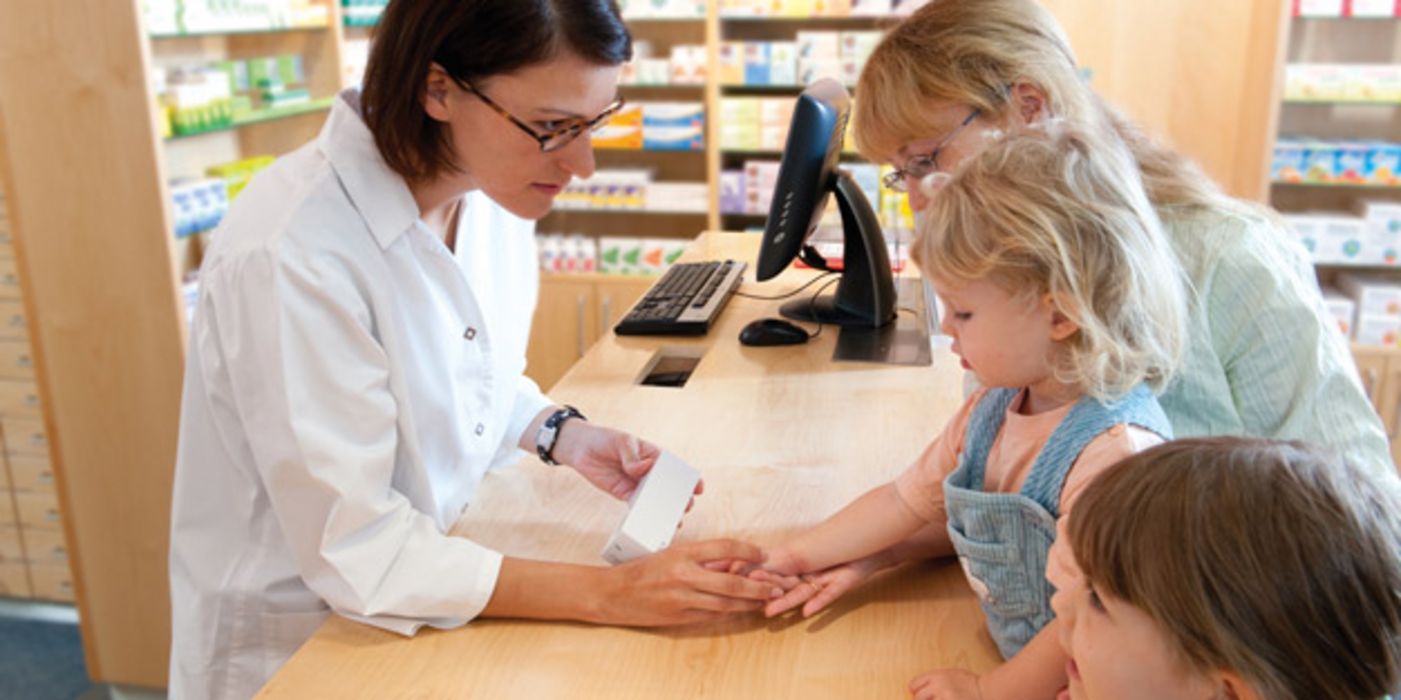 Apothekerin berät Kundin mit Kindern zu Hautproblemen