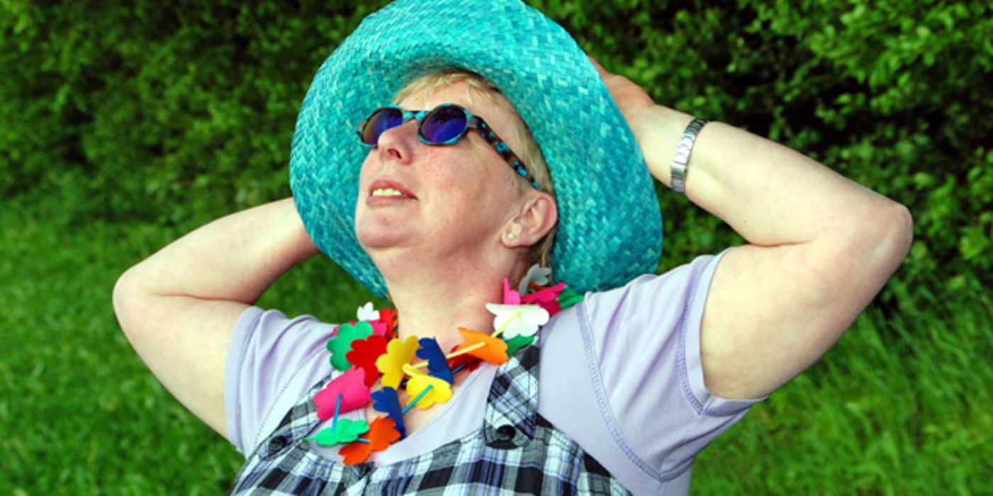 Ältere Frau mit Sonnenhut und -brille.