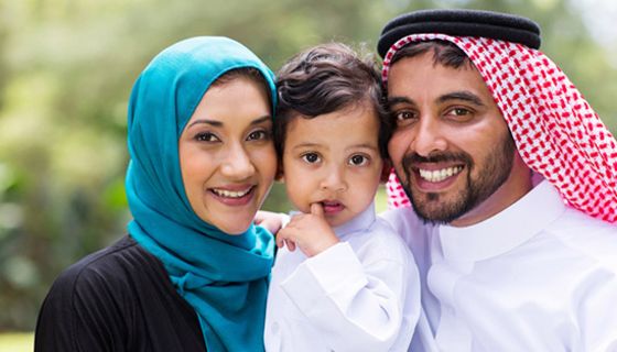 Saudi-Arabisches Ehepaar mit kleinem Kind, ca. 2 Jahre, in der Mitte, Eltern lächeln in Kamera