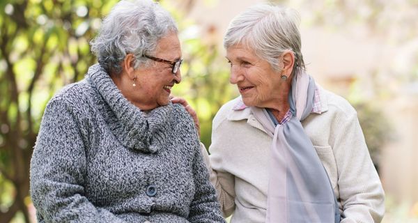 Zwei ältere Damen auf einer Bank, ins Gespräch vertieft.