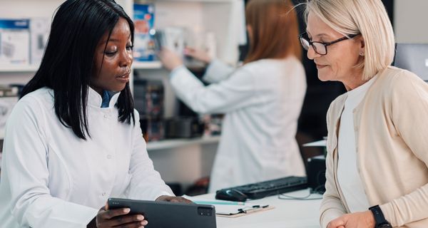 Eine Apothekerin zeigt einer Kundin ewtas auf einem Tablet.