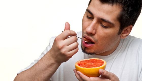 Mann isst Grapefruit.