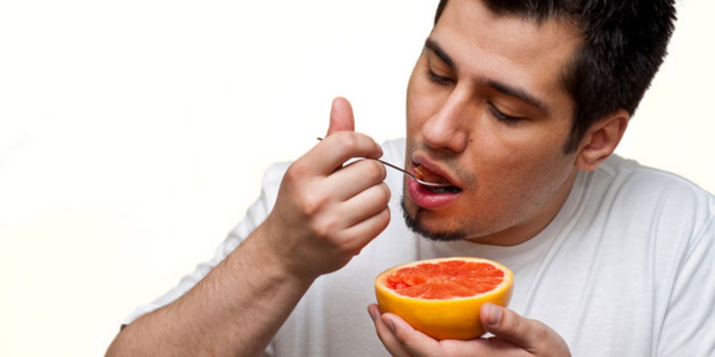 Mann isst Grapefruit.