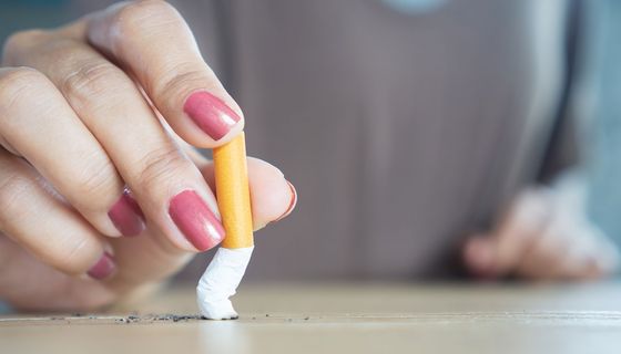 Frau drückt Zigarette auf Tisch aus