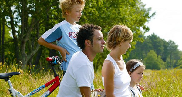 Profile von links, Junge, ca. 10, Vater, Mutter, Tochter, ca. 6, links Jungenfahrrad, Hintergrund sommerliche Natur