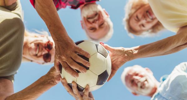 Gruppe von älteren Menschen, halten einen Fußball in der Hand.