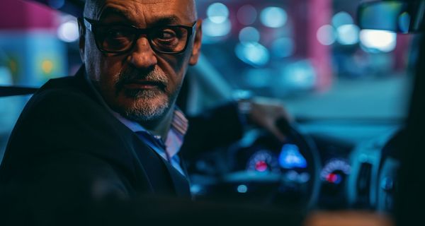 Älterer Mann, parkt in der Nacht rückwärts mit dem Auto ein.