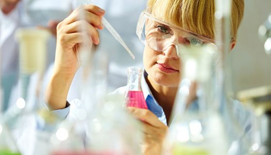 Forscherin im Labor mit Schutzbrille beim Pipettieren