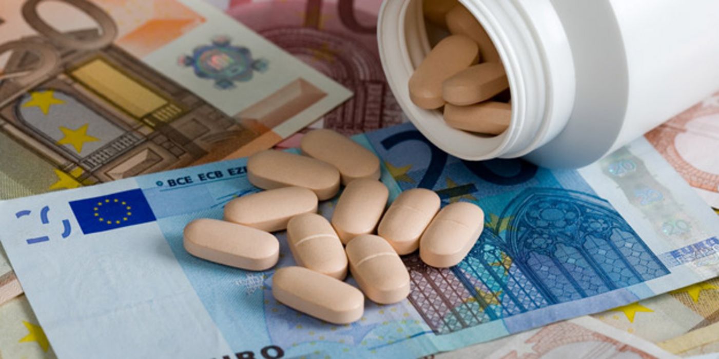 Plastikdose mit ausgeleerten Tabletten auf Euro-Scheinen