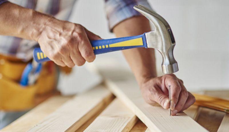 Mann hämmert auf einen Nagel.