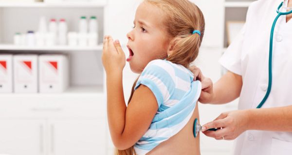 Mädchen im Grundschulalter bekommt beim Arzt den Rücken mit Stethoskop abgehorcht während sie hustet
