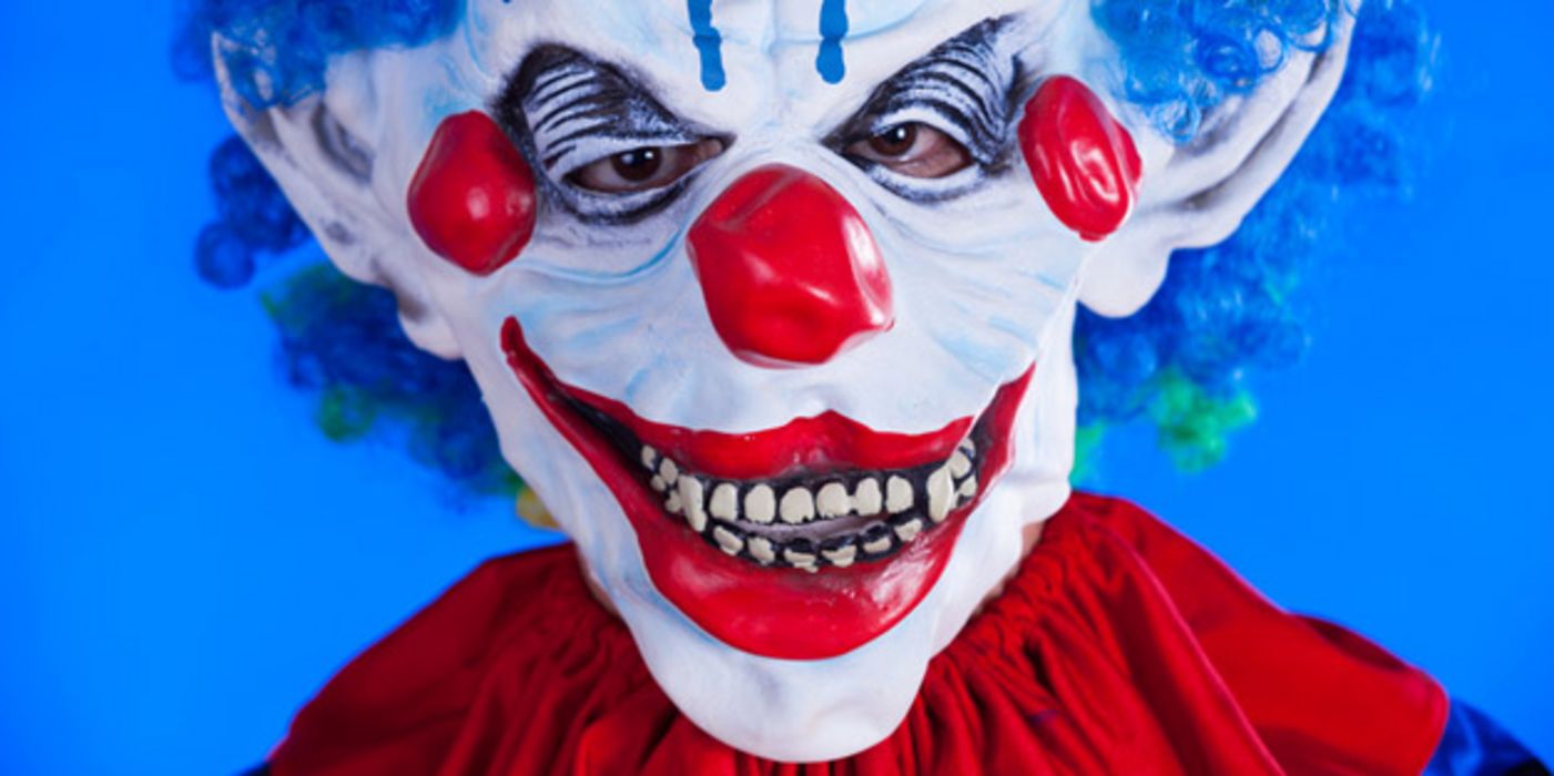 Nahaufnahme Horrorclownmaske (rot-weiß-blaues Gesicht, blaue Haare, roter Umhang)