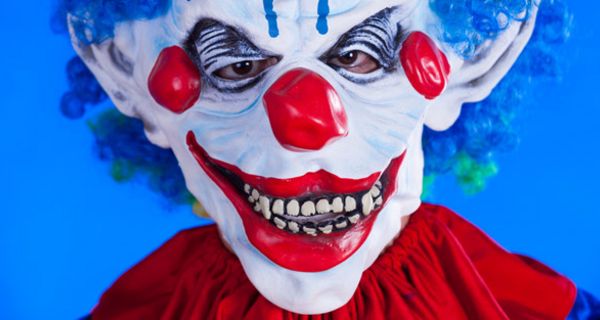 Nahaufnahme Horrorclownmaske (rot-weiß-blaues Gesicht, blaue Haare, roter Umhang)