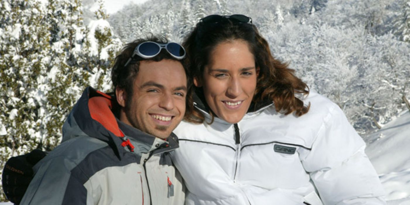 Junges Paar in Skikleidung vor verschneiter Landschaft
