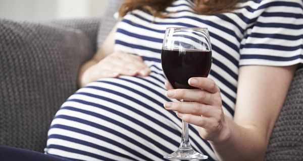Schwangere Frau mit Weinglas in der Hand