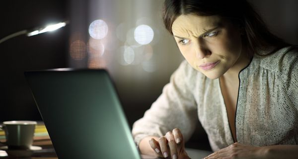 Frau blickt kritisch auf einen Laptop-Bildschirm
