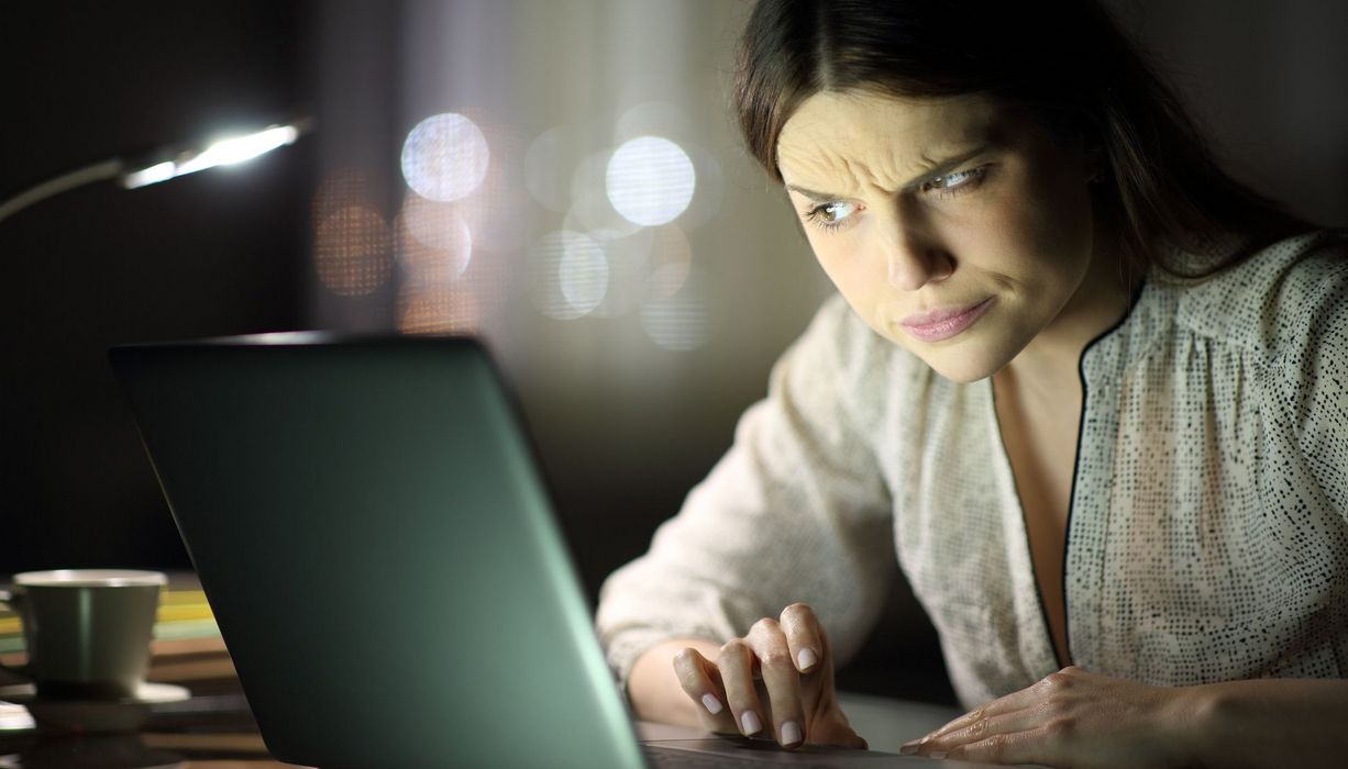 Frau blickt kritisch auf einen Laptop-Bildschirm