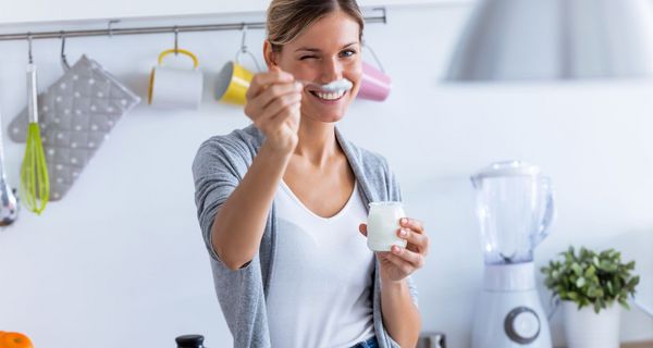 Junge Frau, hält einen Löffel mit Jogurt in die Kamera.