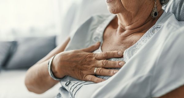 Frau, hält sich eine Hand auf die Brust.