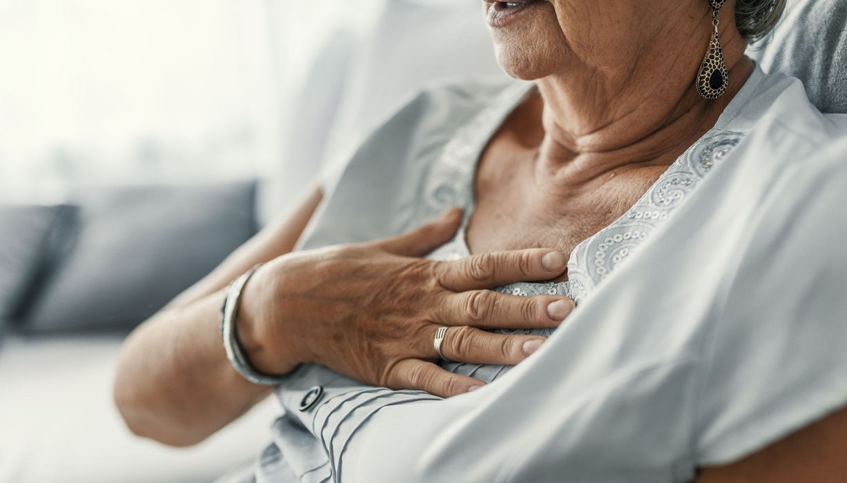 Frau, hält sich eine Hand auf die Brust.