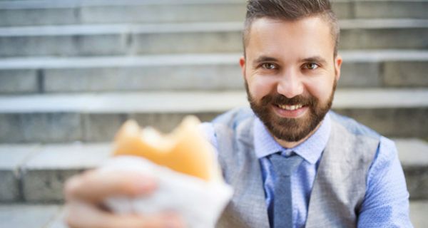 Mann hält Hamburger in der Hand.