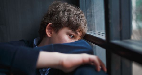 10-jähriger Junge, schaut traurig aus dem Fenster.